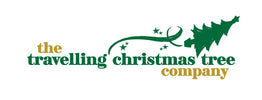 The logo for 'the travelling christmas tree company' on a plain white background, featuring green and gold text with a green Christmas tree silhouette and ribbon graphic.